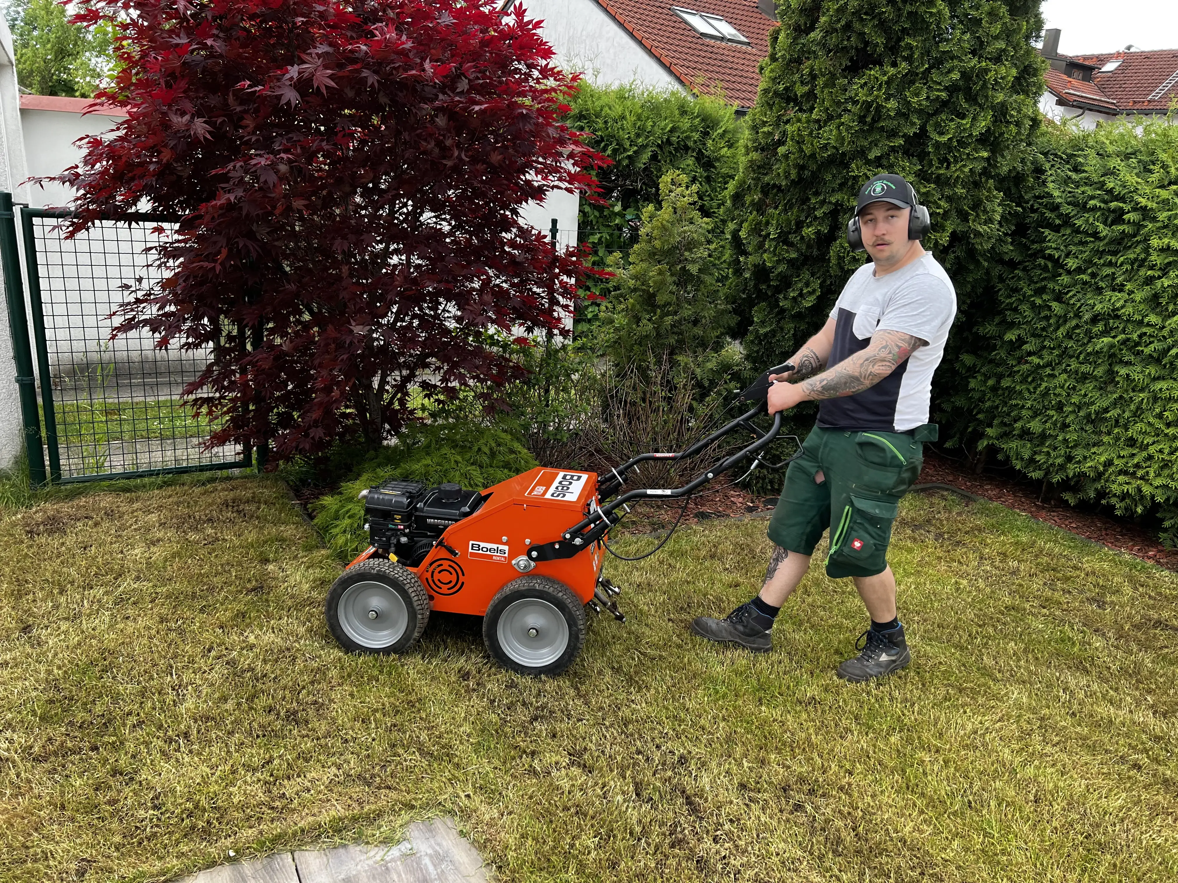 Gärtner vertikutiert einen Rasen